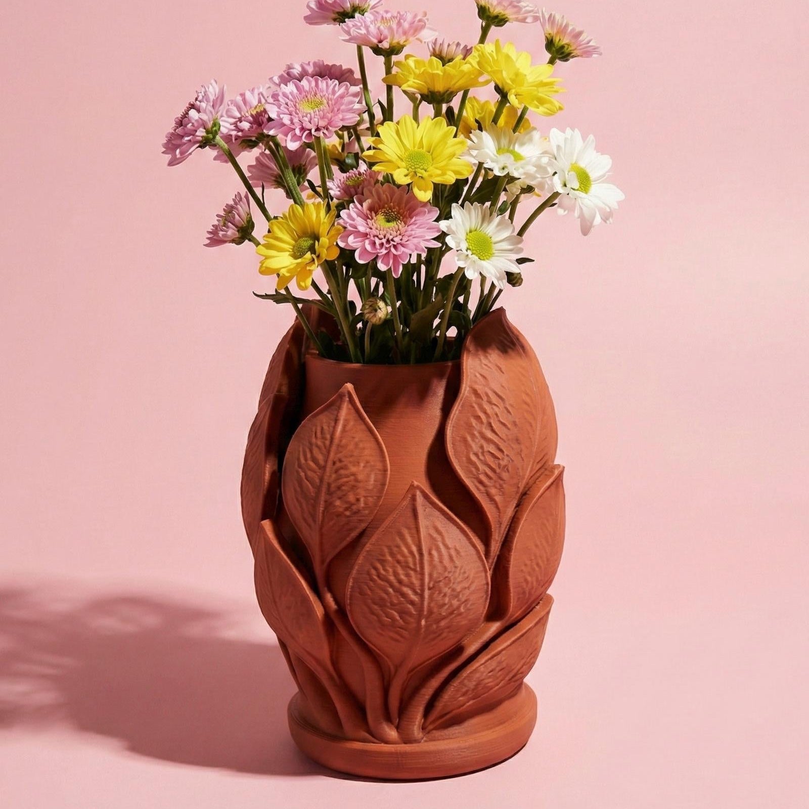Terracotta vase with floral design filled with flowers on a pink background